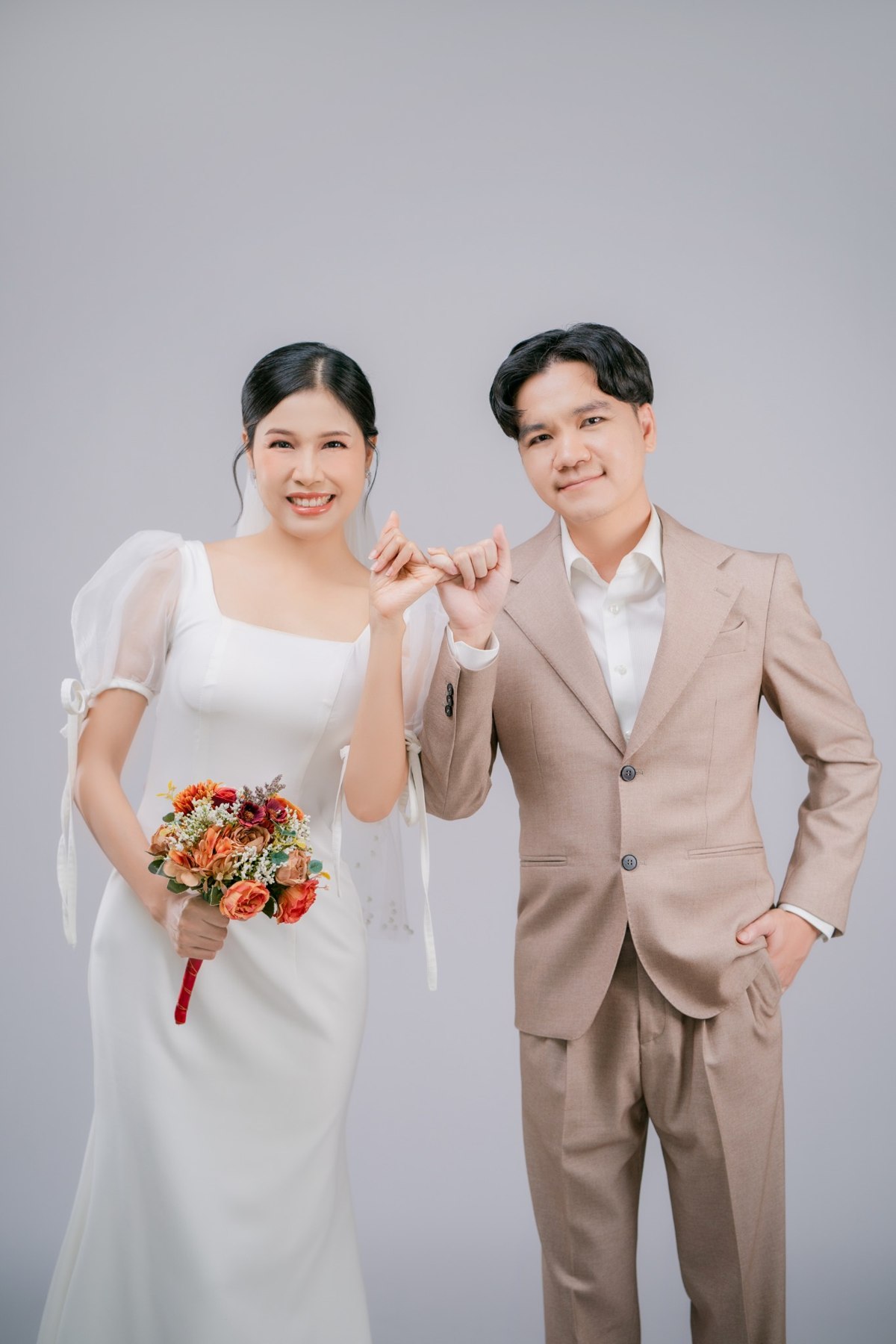 Amm and Hrung holding hands in their wedding outfits